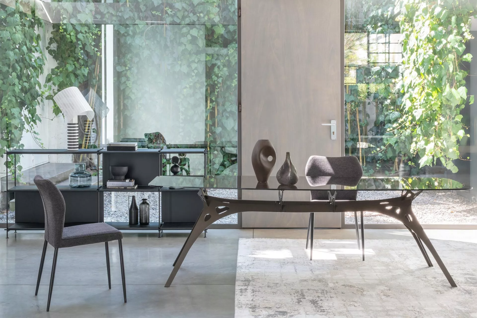 Angle chair by Peressini with sharply slanted backrest and sleek metal legs, upholstered in light grey fabric.