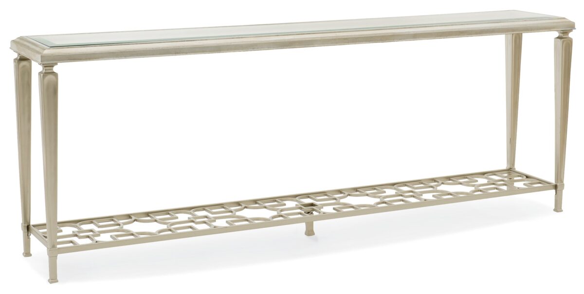 A sleek console table featuring a clear glass top with a 1¼" bevel, supported by tall metal legs and a metal fret-patterned shelf in Taupe Silver Leaf.