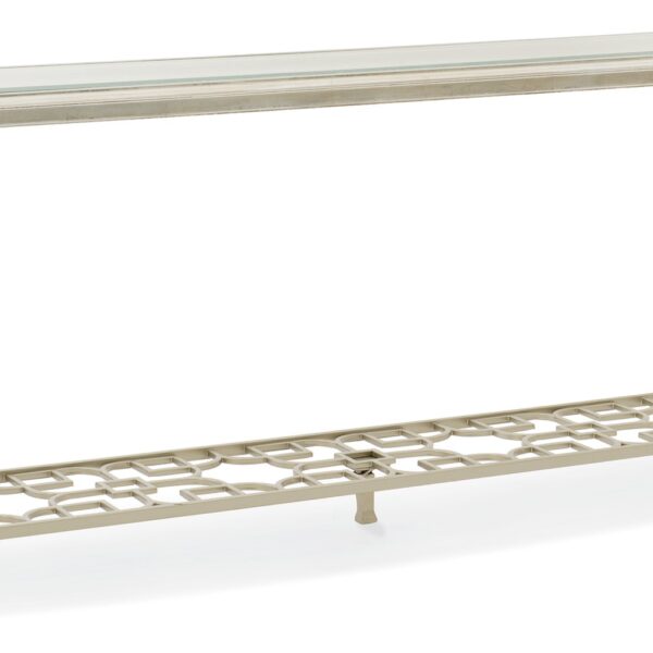 A sleek console table featuring a clear glass top with a 1¼" bevel, supported by tall metal legs and a metal fret-patterned shelf in Taupe Silver Leaf.