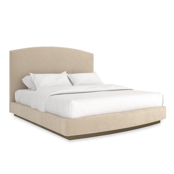 "Caracole Artois King Bed featuring an arched headboard, fully upholstered in pumice-colored performance faux suede, with a wood plinth base finished in Brushed Gold paint."