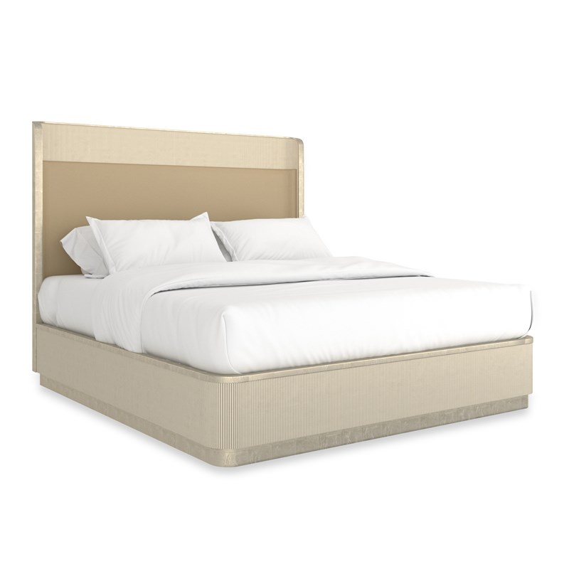 Caracole Fall In Love King Bed featuring a softly curved platform design with a reeded upper headboard panel, upholstered in rich Camel pebbled leather, and finished in Dark Chocolate with Whisper of Gold metal trim accents, set on a plinth base.