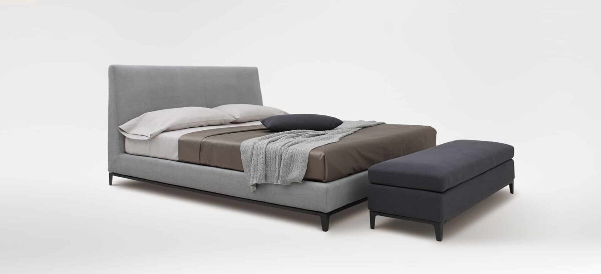 Elegant upholstered bed with curved headboard and modern design by Camerichusa.