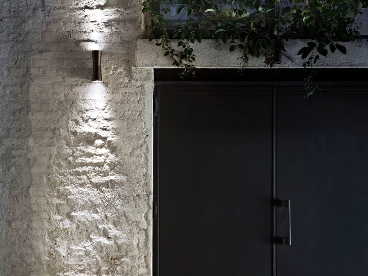 An architectural Flos Clessidra 20°+20° lamp, made of die-cast aluminum with PMMA diffusers, designed to produce sharp, symmetrical uplight and downlight, ideal for emphasizing vertical surfaces.