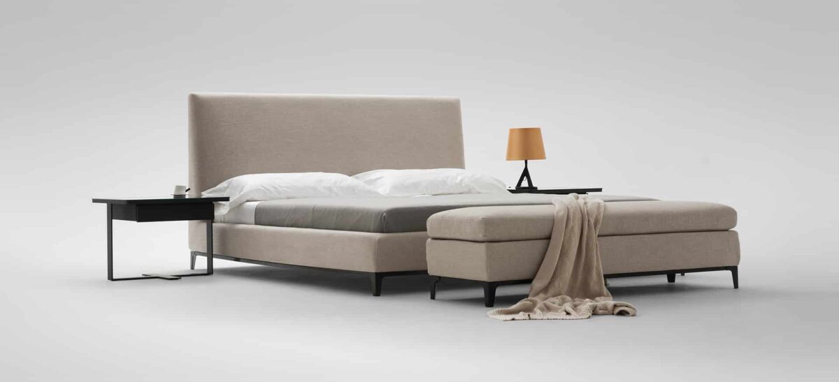 Elegant upholstered bed with curved headboard and modern design by Camerichusa.