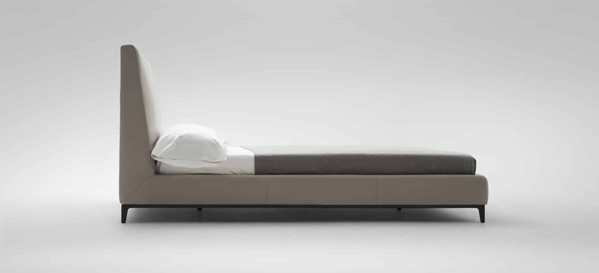 Elegant upholstered bed with curved headboard and modern design by Camerichusa.