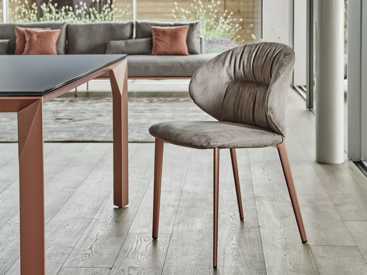 Mirage dining table by Bontempi in modern open-plan interior with satin-matt dove grey glass top and polished steel legs.