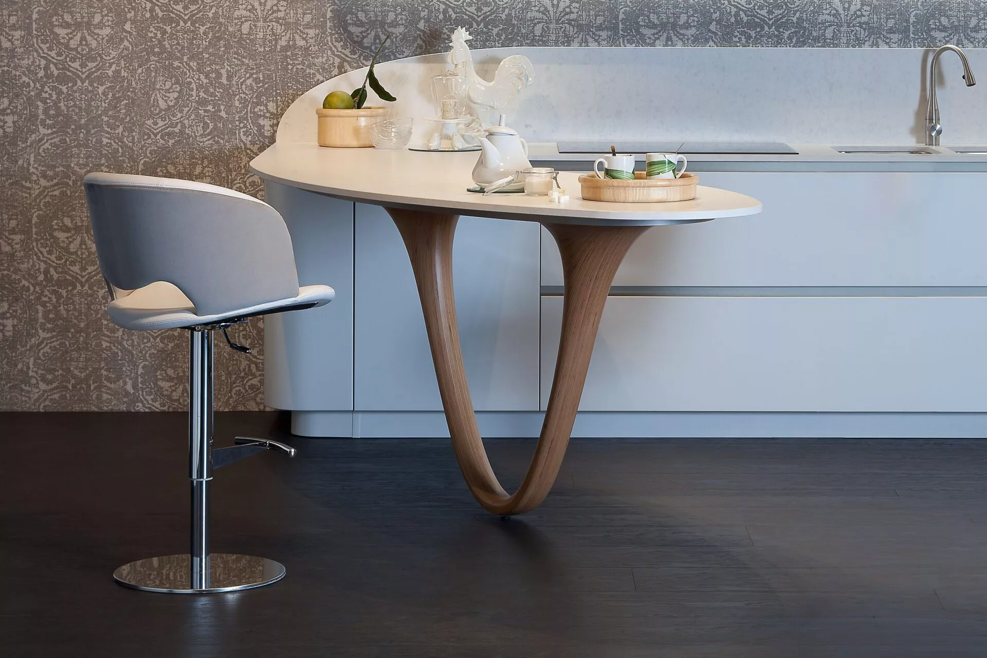 Fashion chair by Peressini Casa upholstered in soft grey fabric with a curved plywood shell and polished chrome sled base, photographed in a minimalist white studio.