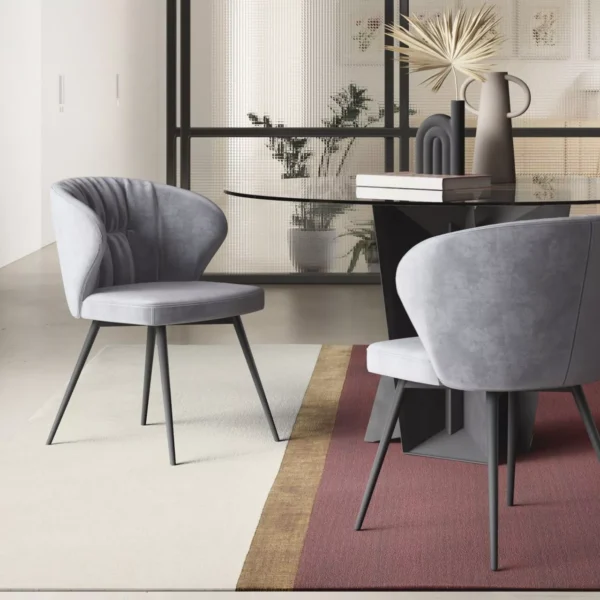 Ingrid chair in powder-blue velvet with gently flared armrest wings, standing on slender black metal legs on a pale wood floor.