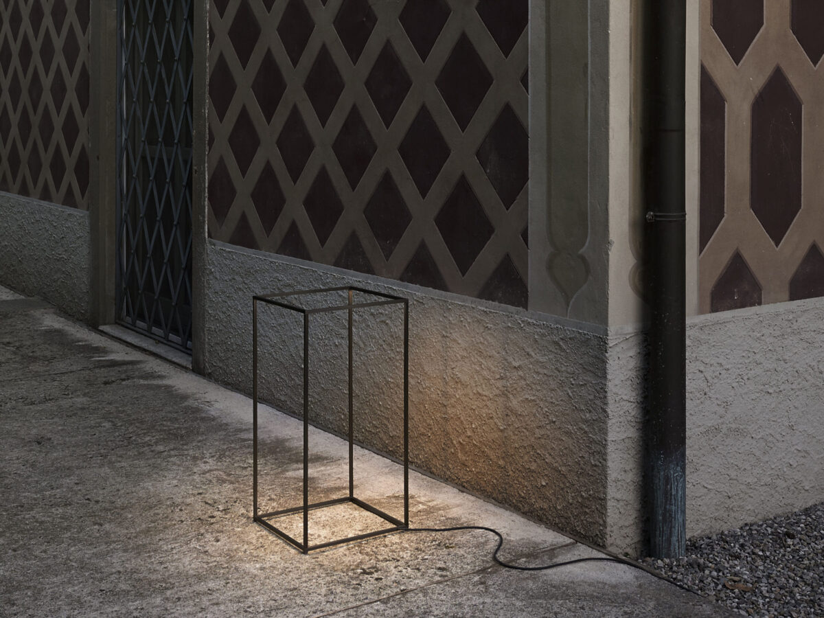 Flos Ipnos Outdoor lamp glowing softly at night, showcasing its invisible light source within a metal frame.