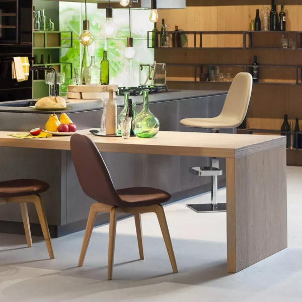 Kube Chair by Peressini with sleek, minimalist design, upholstered in high-quality leather or fabric options, and supported by a customizable metal base in finishes like Black Chrome, Brushed Gold, and Satin Nickel.