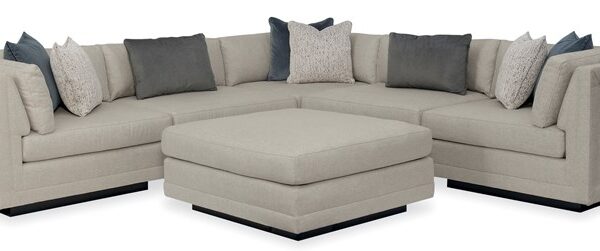 Caracole Fusion 6-Piece Sectional featuring a neutral, menswear-inspired tweed upholstery, recessed wood plinth base in Simply Black, cut-out frame detailing, and contrasting deep gunmetal grey accent pillows in velvet and corduroy textures.
