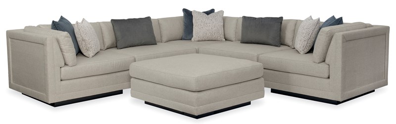 Caracole Fusion 6-Piece Sectional featuring a neutral, menswear-inspired tweed upholstery, recessed wood plinth base in Simply Black, cut-out frame detailing, and contrasting deep gunmetal grey accent pillows in velvet and corduroy textures.