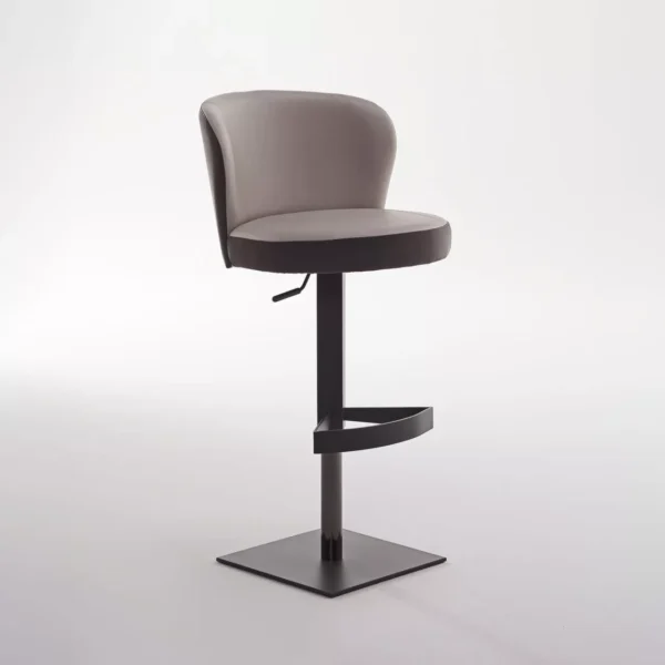 Ocean bar stool by Peressini upholstered in warm grey fabric with a curved low back and brushed stainless steel pedestal base, staged at a white quartz kitchen island.