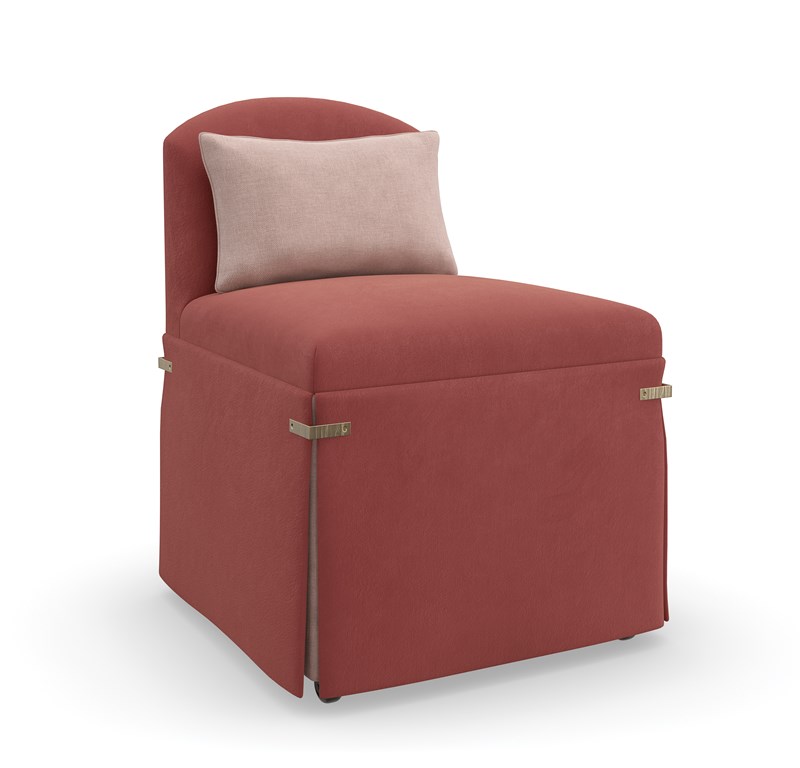 "Bustle Chair by Caracole in dusty rose fabric, featuring a low camelback and dressmaker skirt, cinched with Brushed Gold metal brackets, and equipped with casters for mobility."