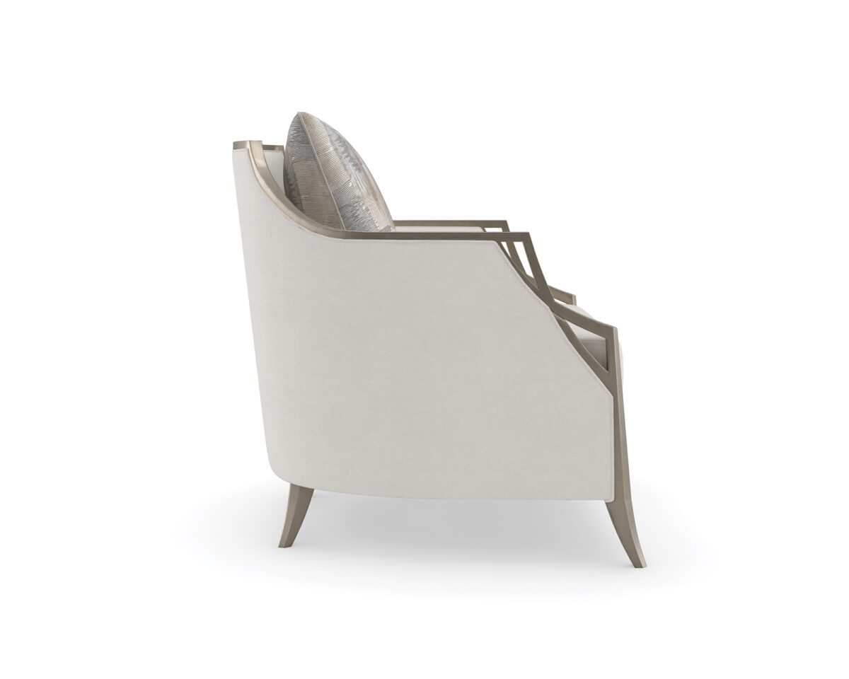 The Caracole X Factor Sofa, a modern classic upholstered in a herringbone performance fabric, featuring a wood-trimmed silhouette with a carved crisscross pattern, gently sloping arms, splayed legs in a metallic Charcoal Leaf finish, and feather-down toss pillows.