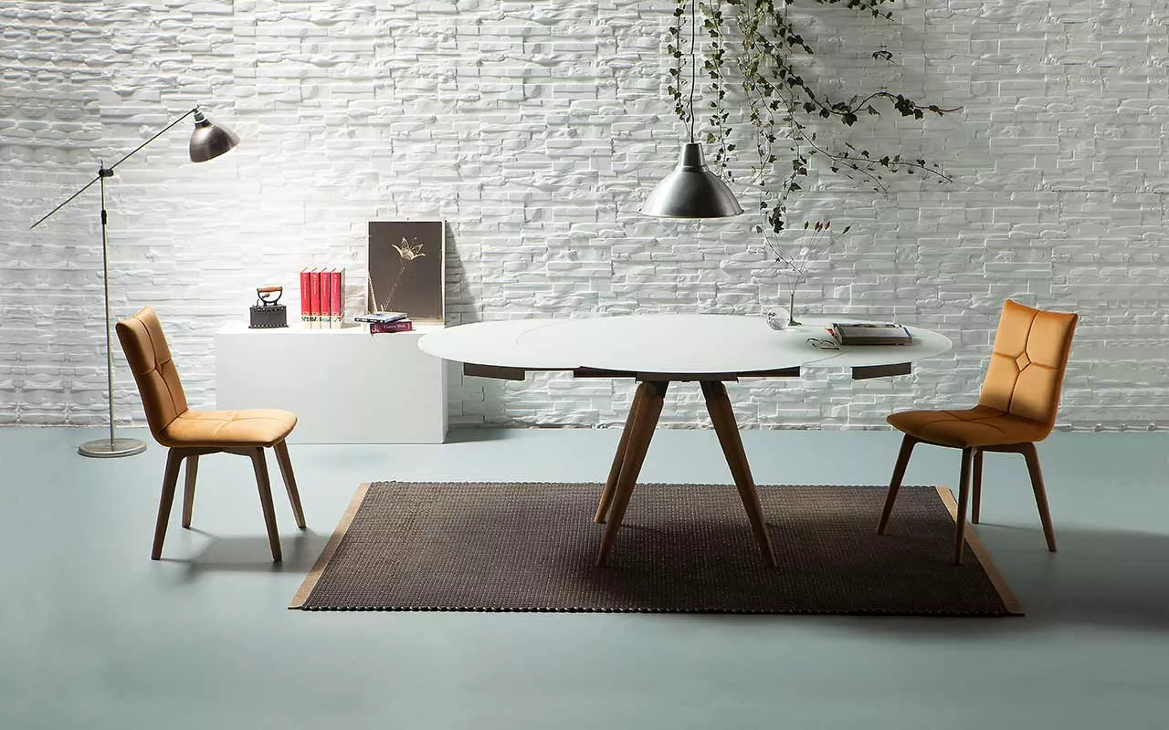 Akemi chair by Peressini with warm tan leather upholstery, featuring a stitched vertical panel backrest and slender chrome sled base, on a white studio backdrop.