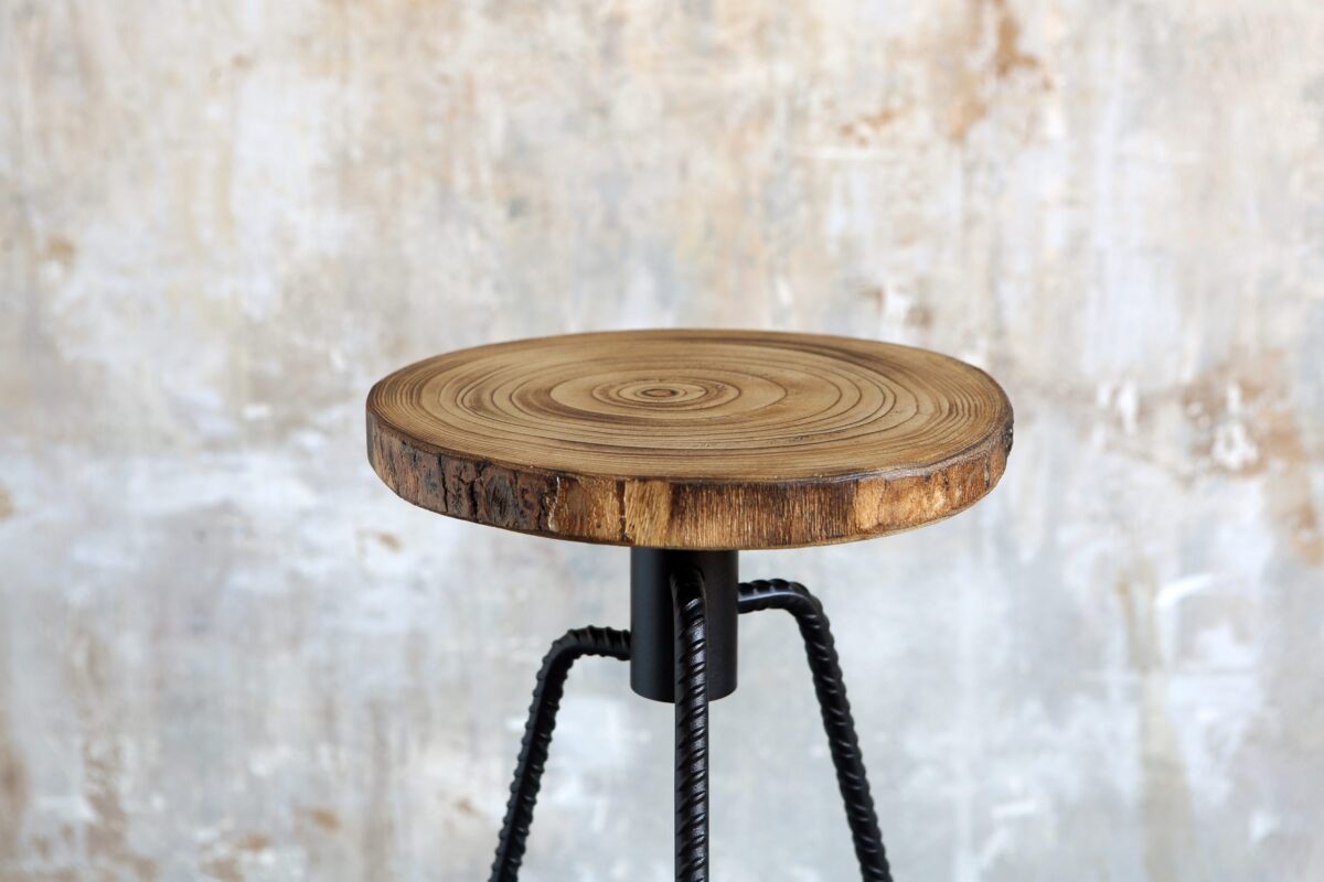 “Group of three NIKITA stools at varying heights, each featuring a wood trunk seat and steel frame, styled in an industrial loft setting.”