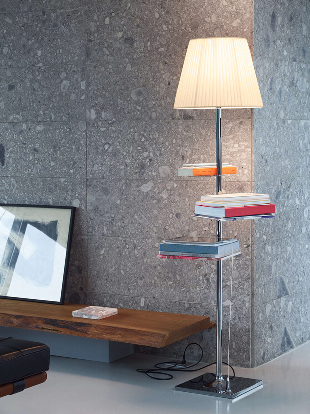 Polished zinc base with built-in USB port supports a lamp with metal rod, diffused fabric or PVC shade and cantilevered book shelves.