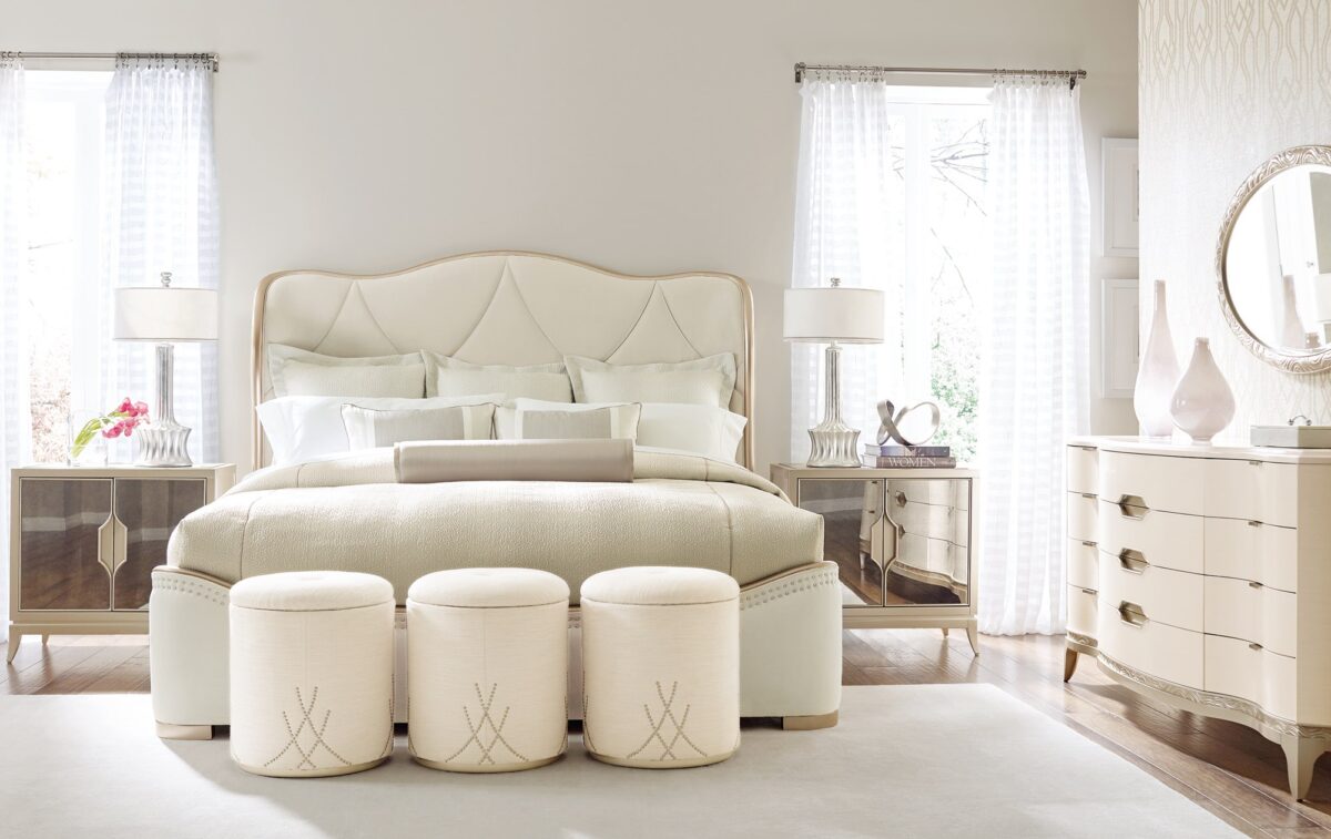 Caracole ADELA Sofa, showcasing a sleek profile with a graceful inward curve, carved ribbon details on the arms, and a dramatic cutout in the back, upholstered in a creamy boucle fabric.