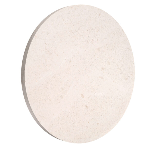 A round Flos Camouflage 240mm outdoor wall lamp made of natural Crema d'Orcia stone, subtly blending into the wall surface while emitting a soft, diffused LED light.