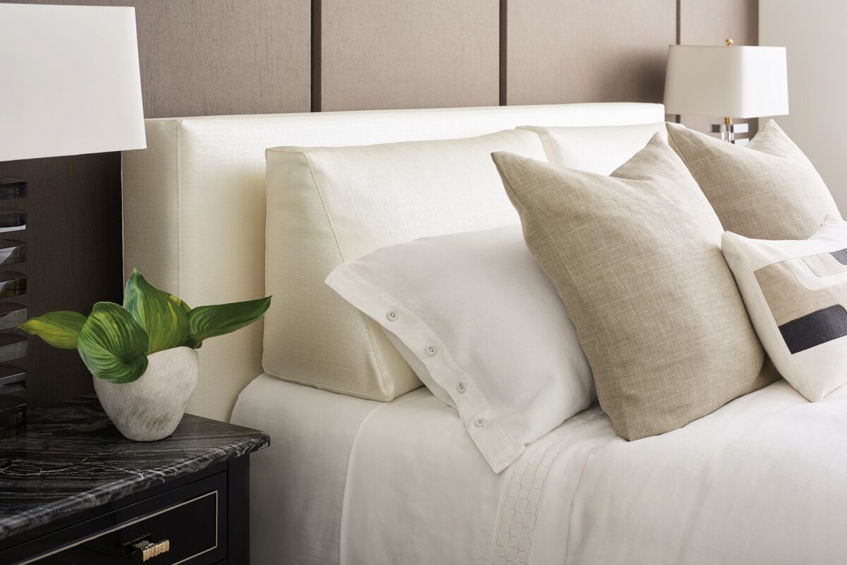 Luxurious upholstered bed with a modern, tailored headboard featuring subtle side wings, THE BOUTIQUE BED by Caracole.