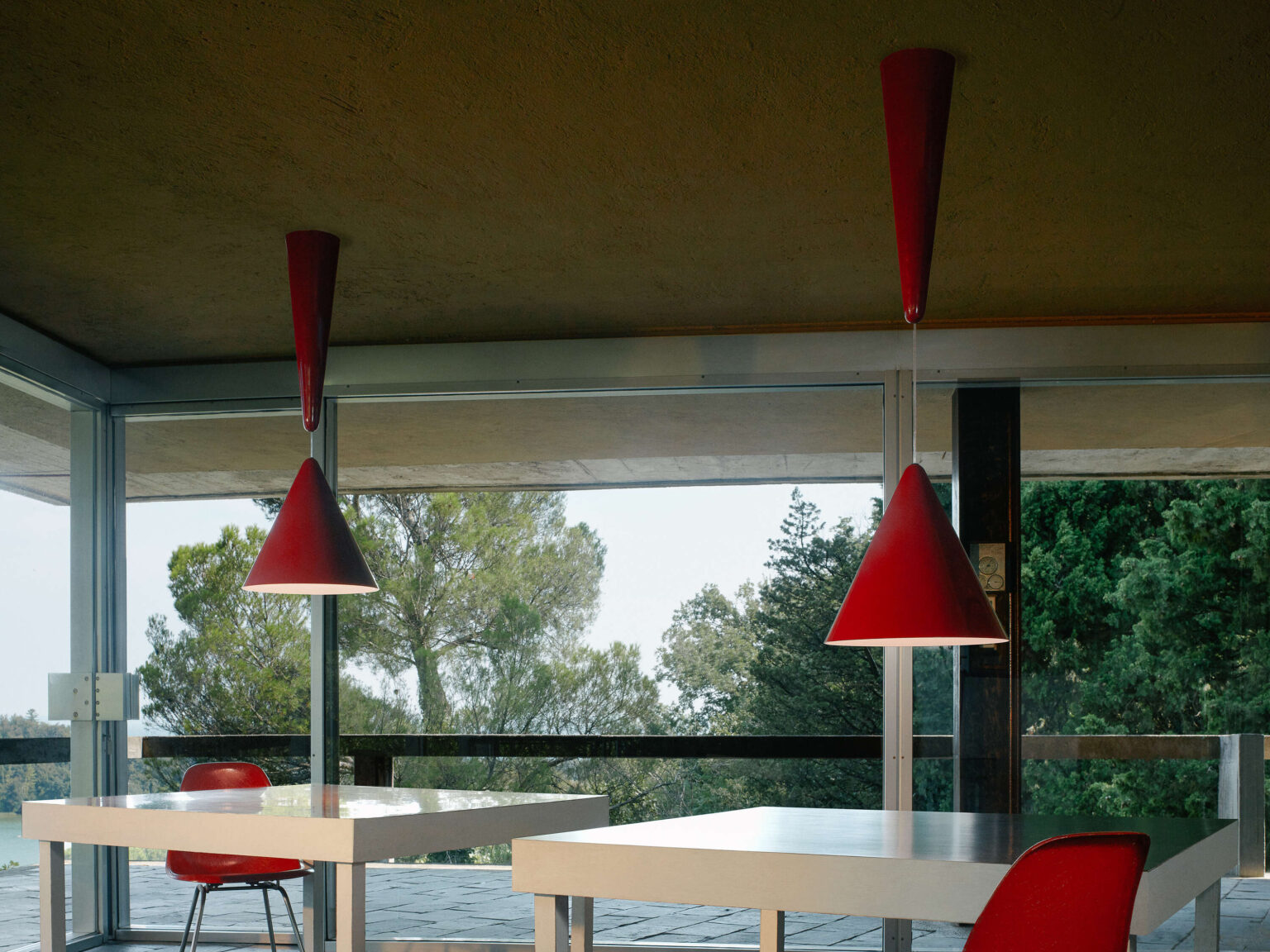 Minimalist white Diabolo pendant with dual conical shades, suspended at mid-level in a neutral-toned dining space.