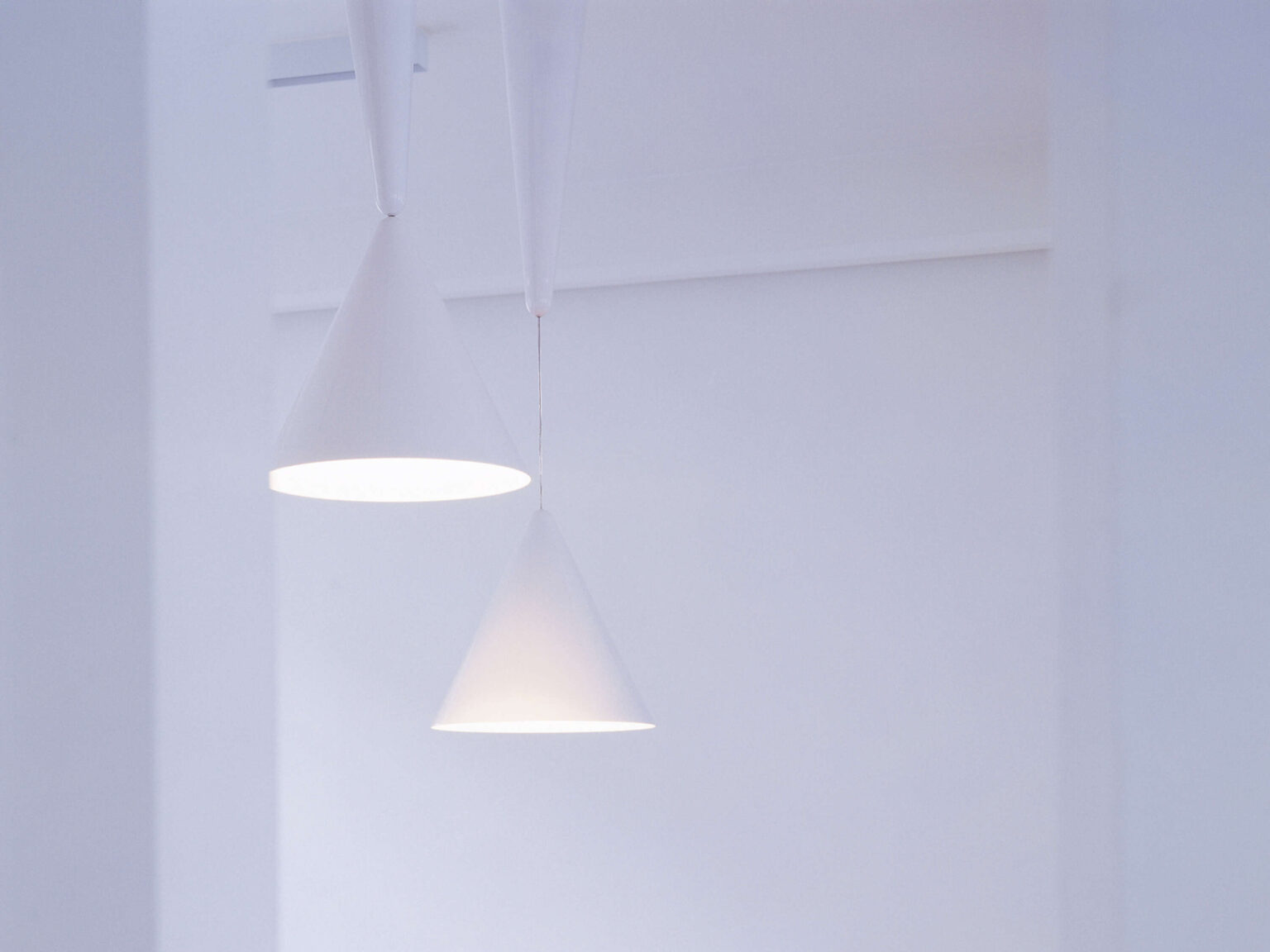 Three Diabolo pendants clustered at different heights in red, gray, and white, creating a sculptural light installation.