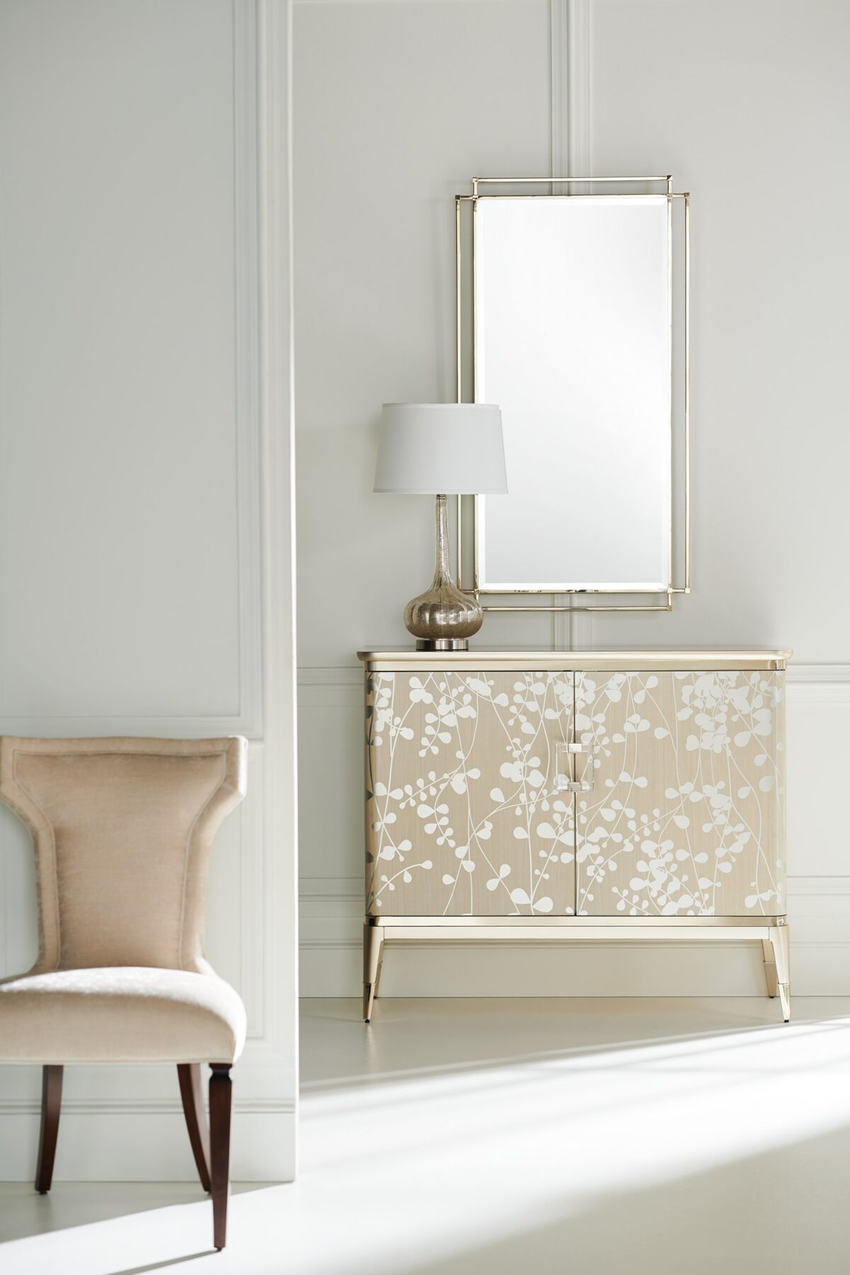 The Caracole "A Shimmer of Light" chest, a transitional storage piece with a shimmering Champagne Shimmer finish, a subtle silkscreened leaf pattern in Taupe, and elegant plated Whisper of Gold trim, ferrules, and hardware.
