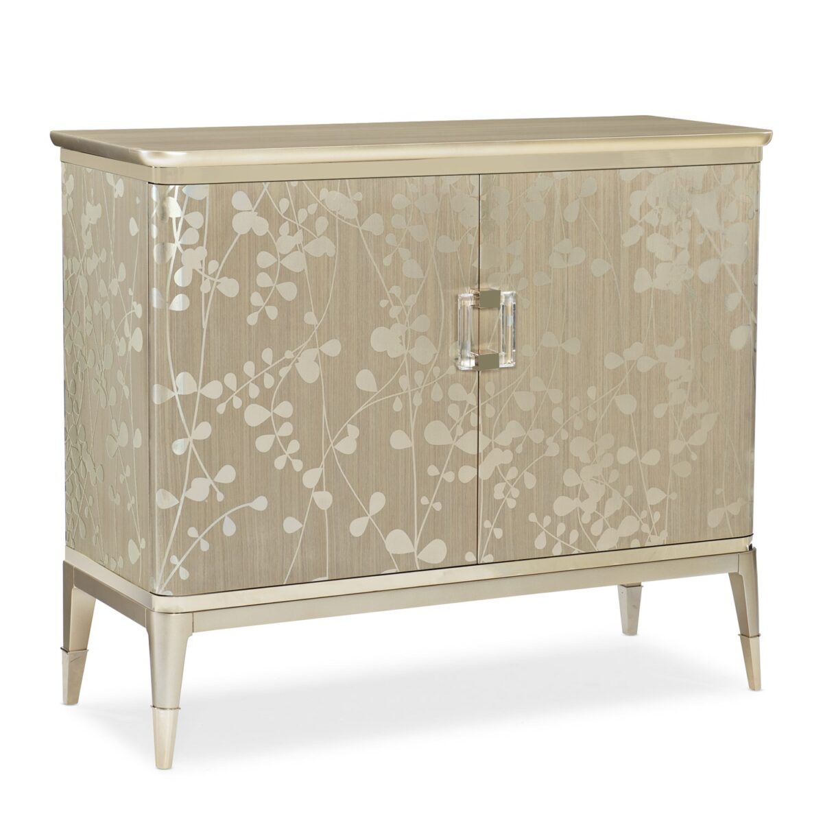 The Caracole "A Shimmer of Light" chest, a transitional storage piece with a shimmering Champagne Shimmer finish, a subtle silkscreened leaf pattern in Taupe, and elegant plated Whisper of Gold trim, ferrules, and hardware.