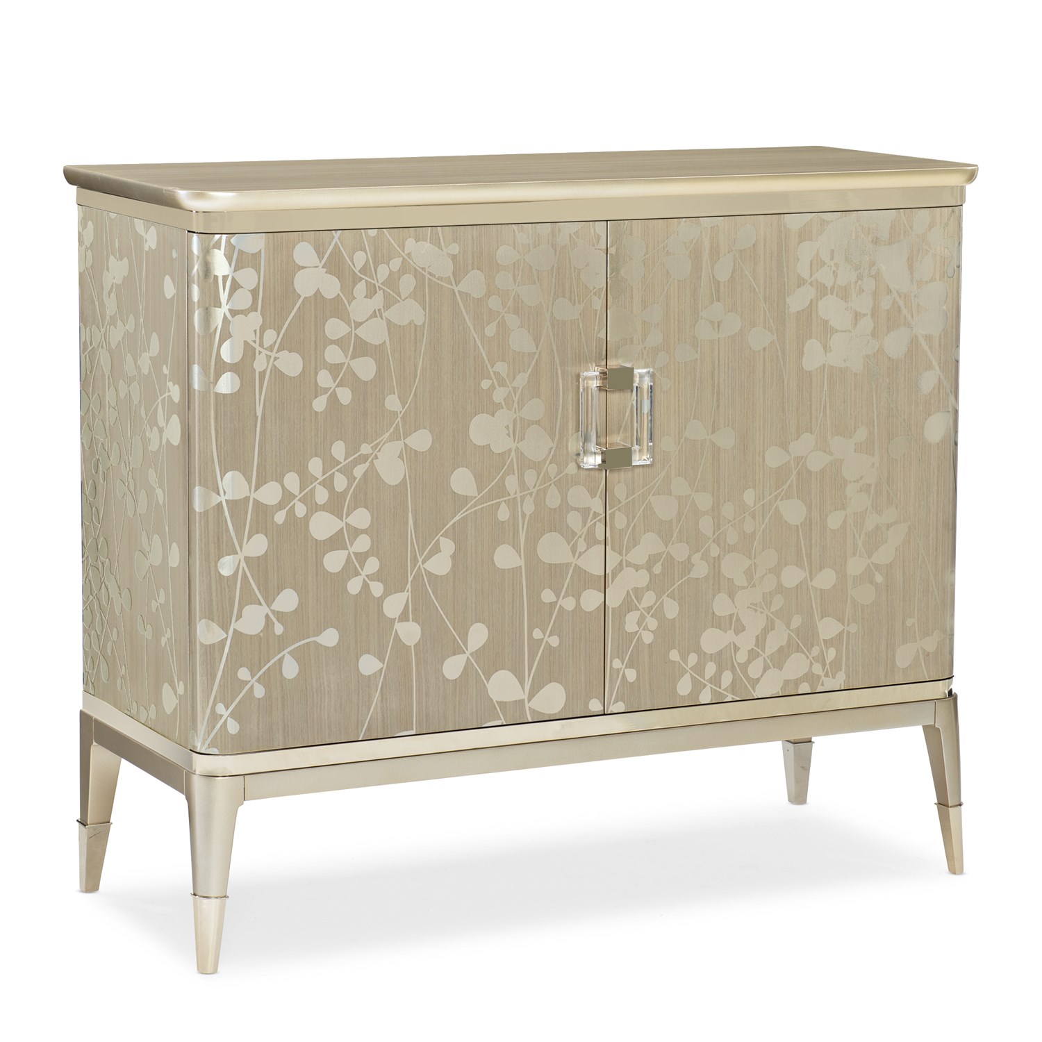 The Caracole "A Shimmer of Light" chest, a transitional storage piece with a shimmering Champagne Shimmer finish, a subtle silkscreened leaf pattern in Taupe, and elegant plated Whisper of Gold trim, ferrules, and hardware.