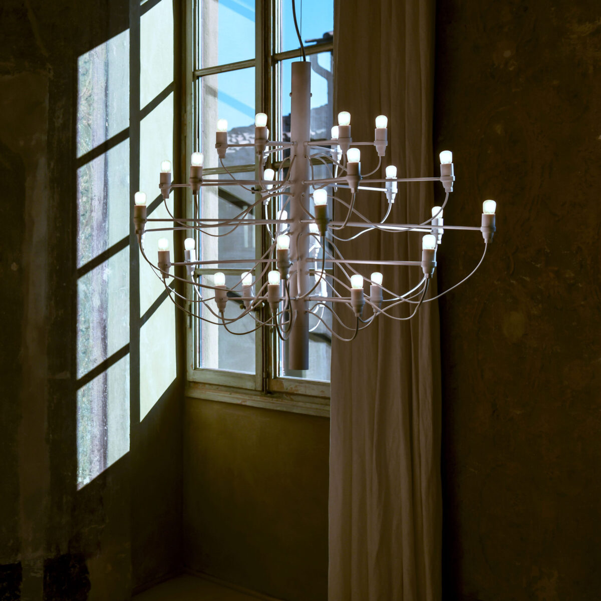 Iconic 2097/30 light fixture by Flos featuring industrial-inspired wiring and glowing clear bulbs.