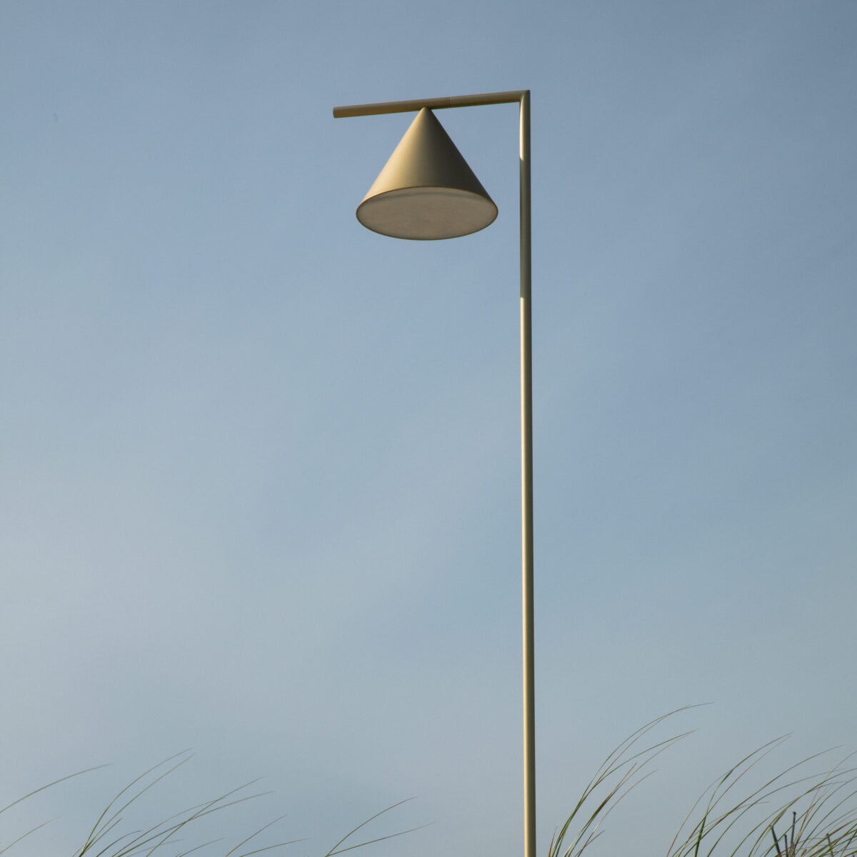Side view of Captain Flint by Flos, showcasing its pivoting brass shade and stable cylindrical lava stone base.