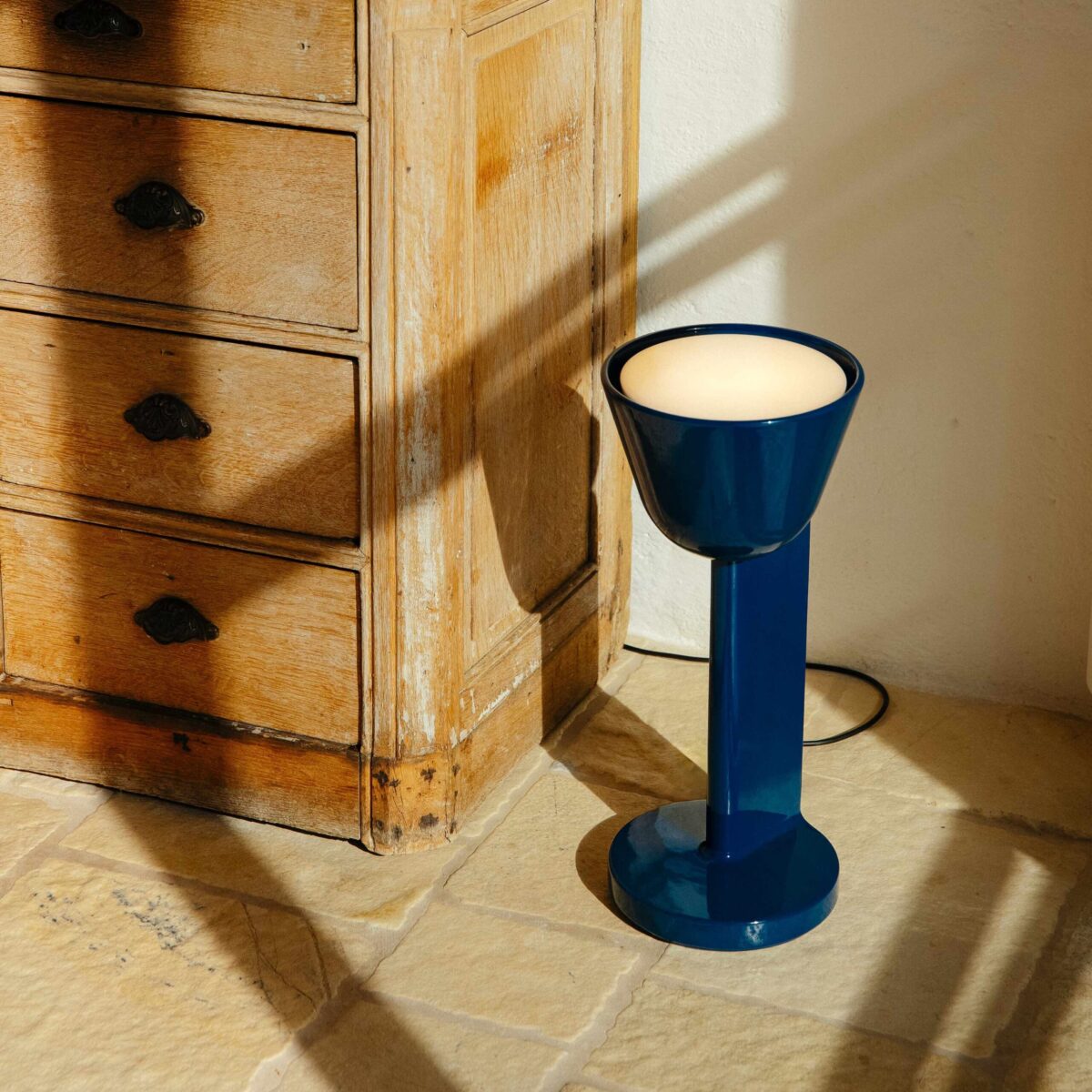 Contemporary ceramic lamp with artisanal glaze and subtle curves, Céramique Down by Flos on a side table.