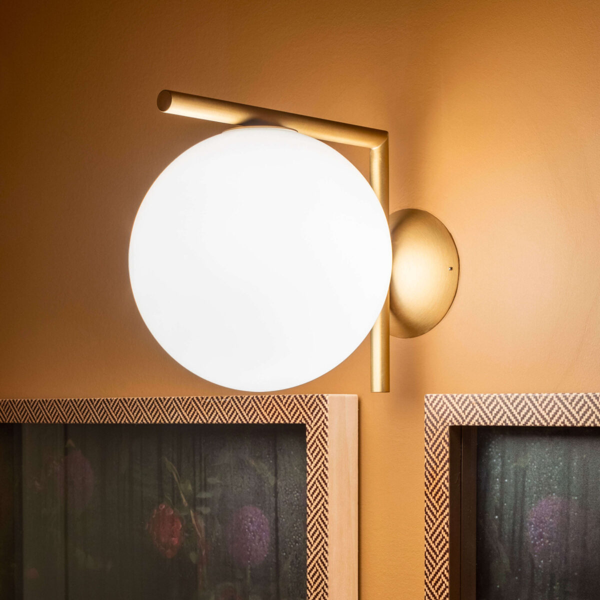 The Flos IC Lights C/W2, an elegant minimalist lamp featuring a smooth, round opal glass globe balanced on a clean-lined metal rod, designed for both wall and ceiling mounting.