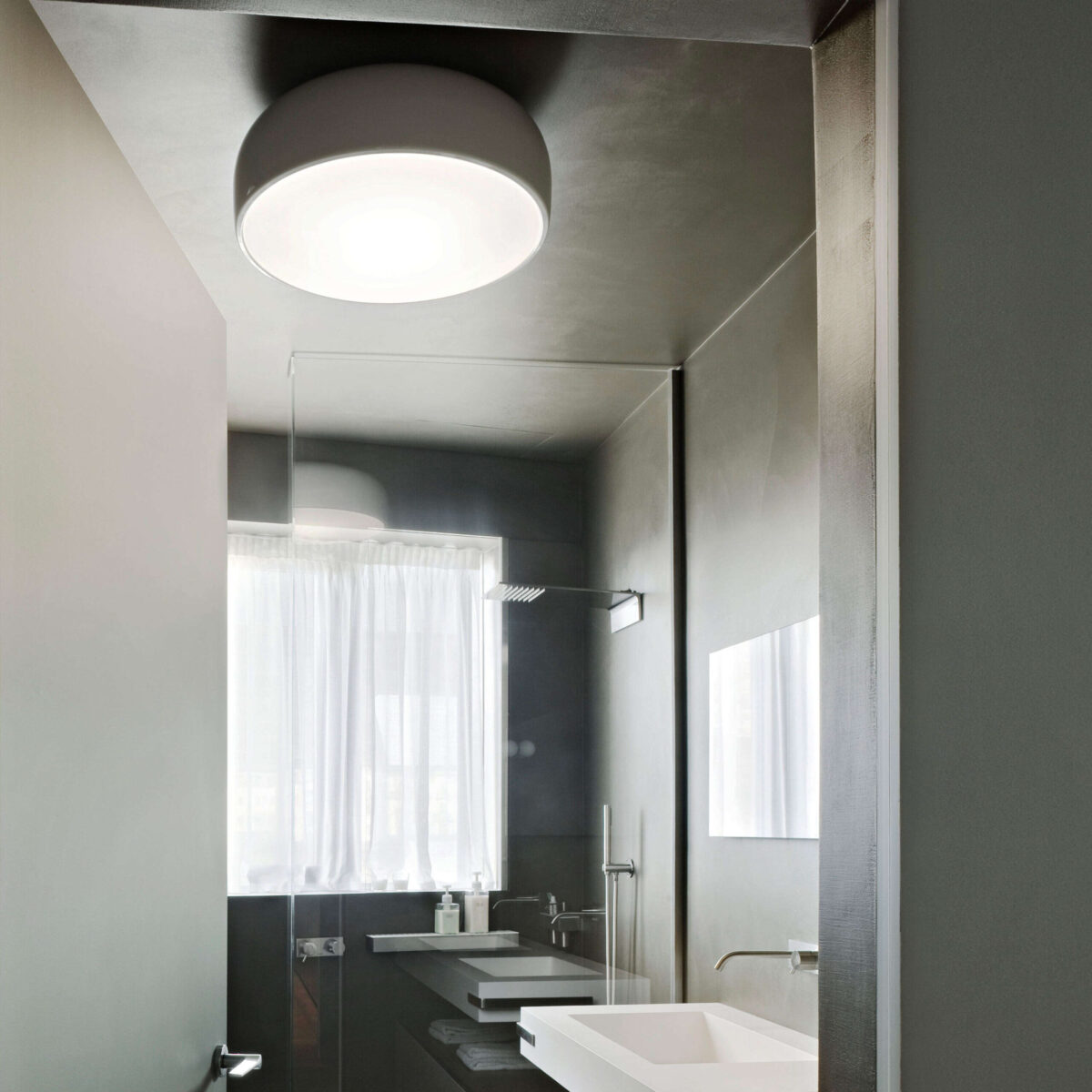 The minimalist Flos Smithfield Ceiling light by Jasper Morrison, a sleek, wide disc-shaped fixture that mounts flush to the ceiling, offering broad and diffused illumination.