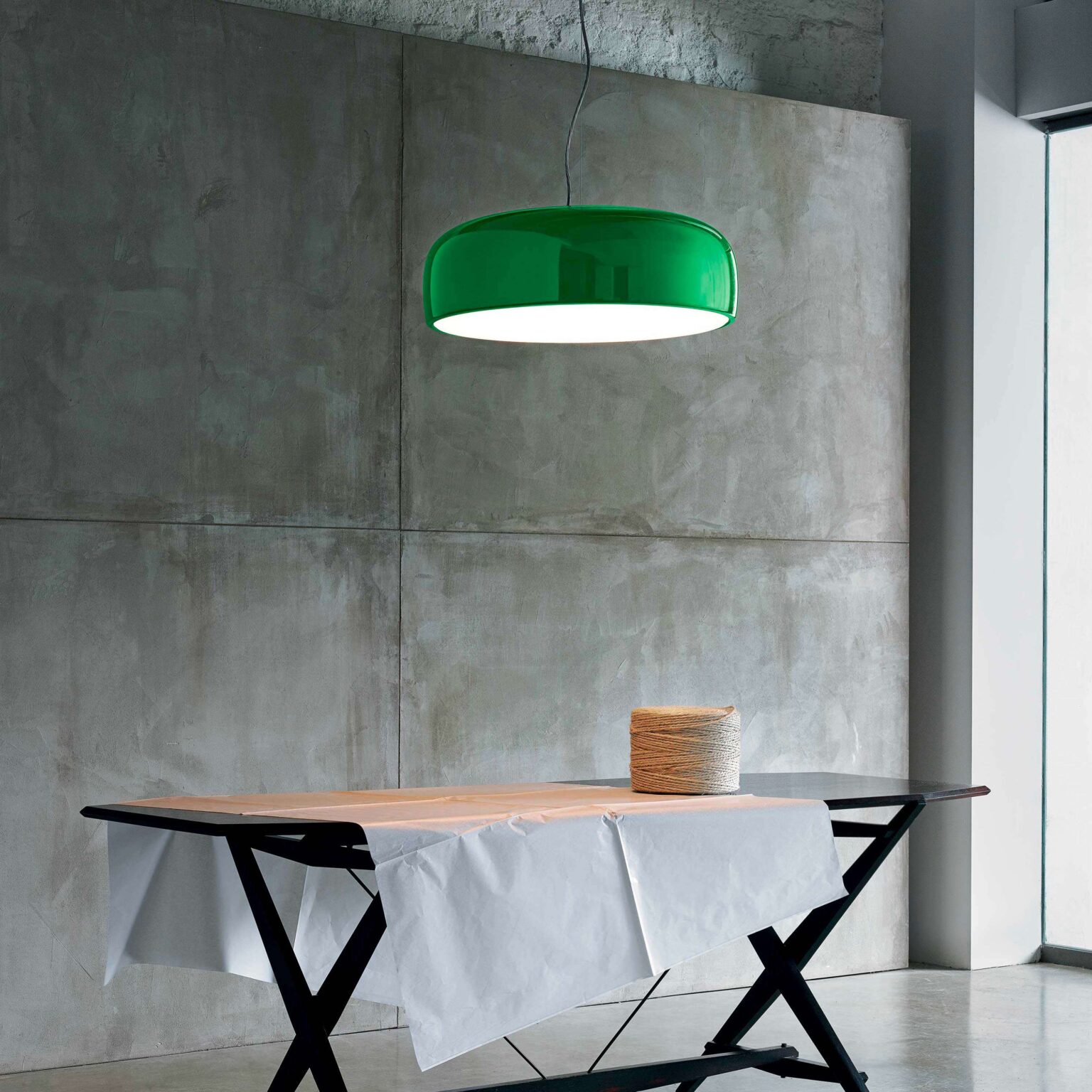 Matte black Smithfield pendant lamp with clean cylindrical form, suspended by a clear cable above a wooden tabletop.