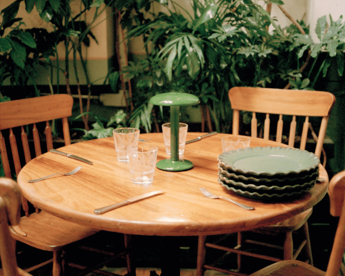 Portable LED lamp in brushed bronze, Gustave Residential by Flos on a contemporary dining table.