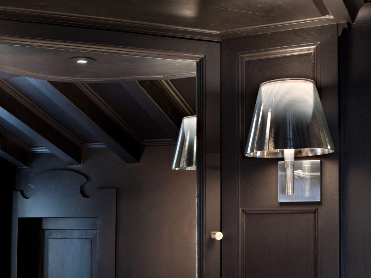 A stylish Flos KTribe Wall light in [specify finish, e.g., "aluminized bronze"], with a classic shade shape mounted on a polished aluminum arm and chrome-plated wall rose, offering both ambient and reading light.