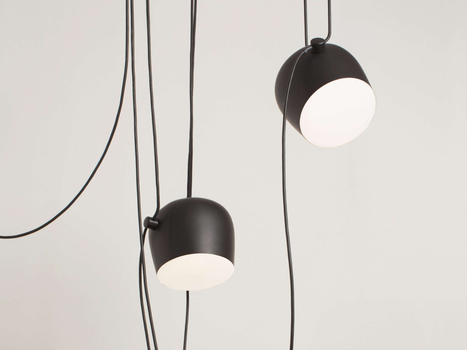 Minimalist Aim single‑head pendant in white, hanging low above a kitchen island, its cable elegantly draped to the ceiling rose.