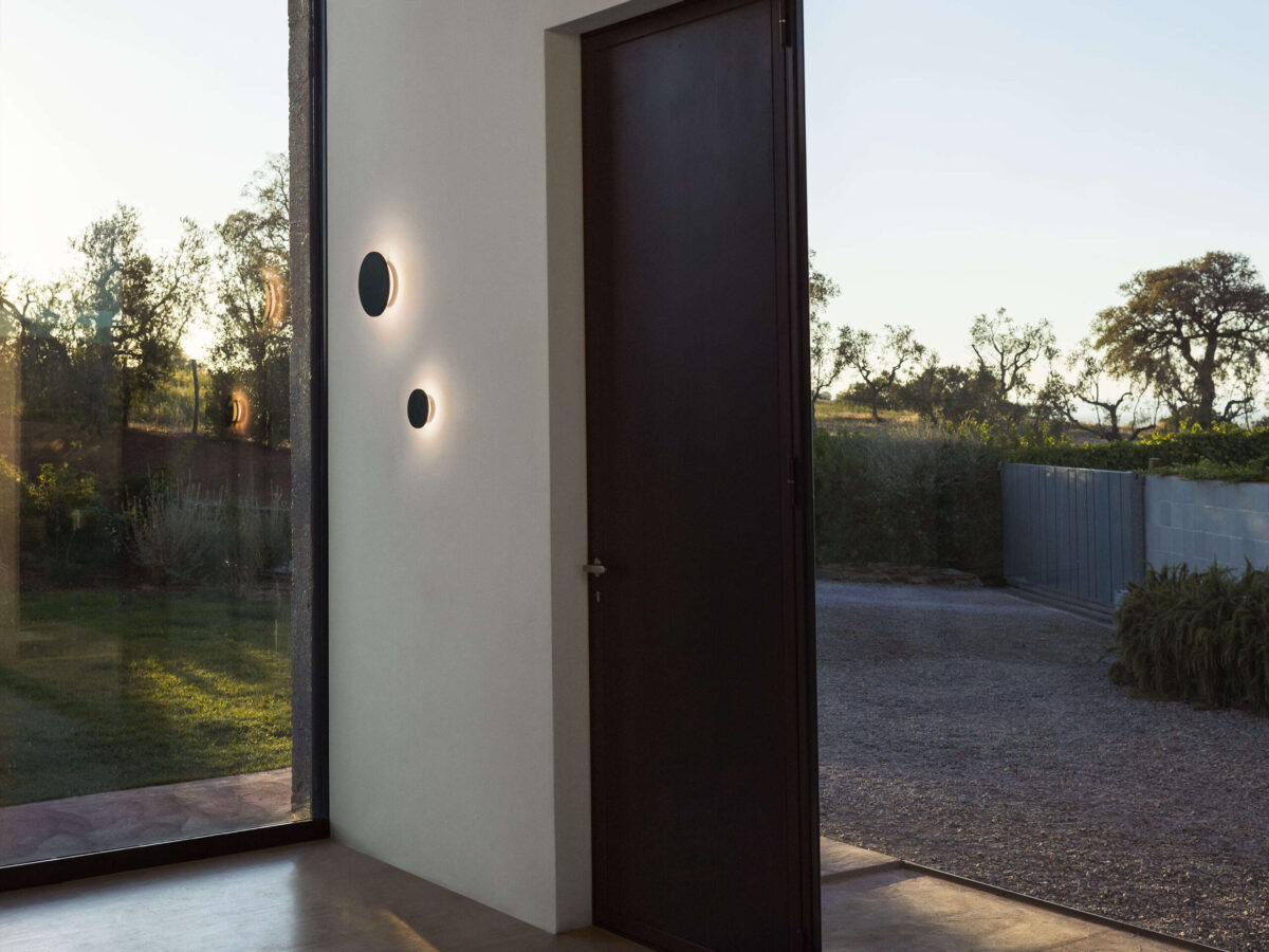 The elegant Flos Camouflage 240mm lamp by Piero Lissoni, a circular wall fixture crafted from creamy beige Crema d'Orcia limestone, designed for seamless architectural integration and ambient outdoor illumination.