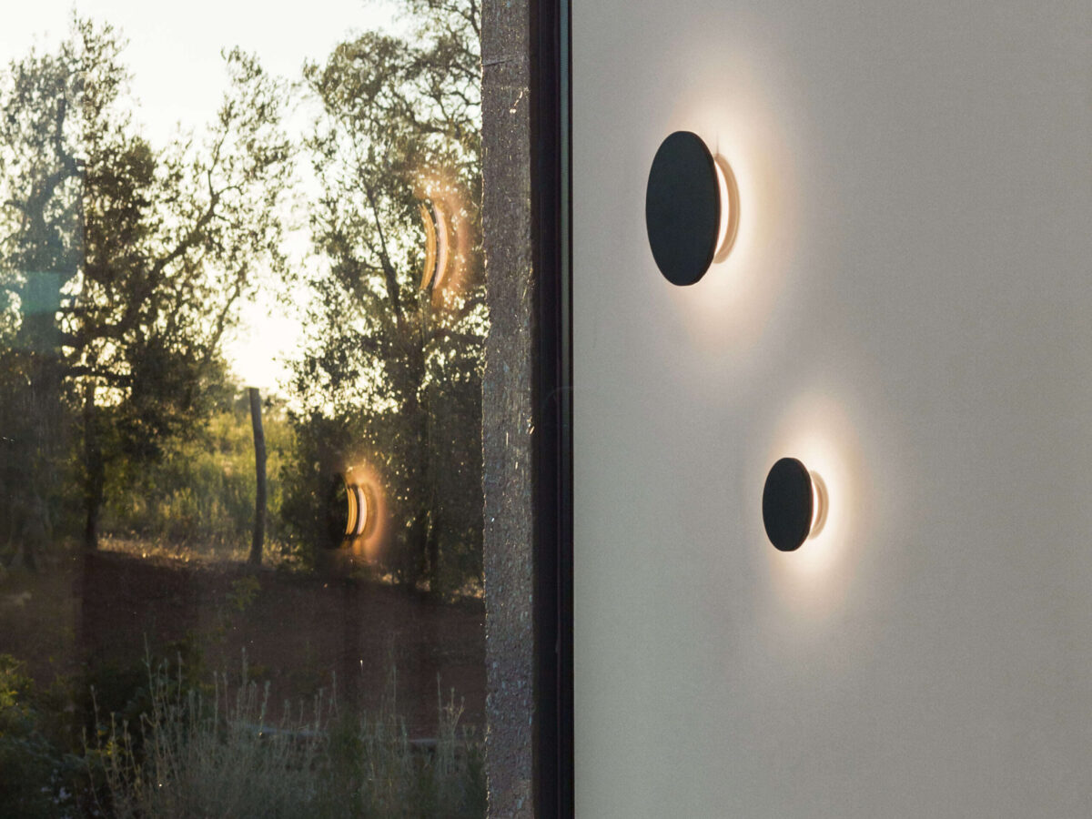 A modern outdoor wall light, the Flos Camouflage 240mm in Crema d'Orcia stone, showcasing its natural texture and color variation, providing a wide 151-degree beam of non-dimmable LED light.