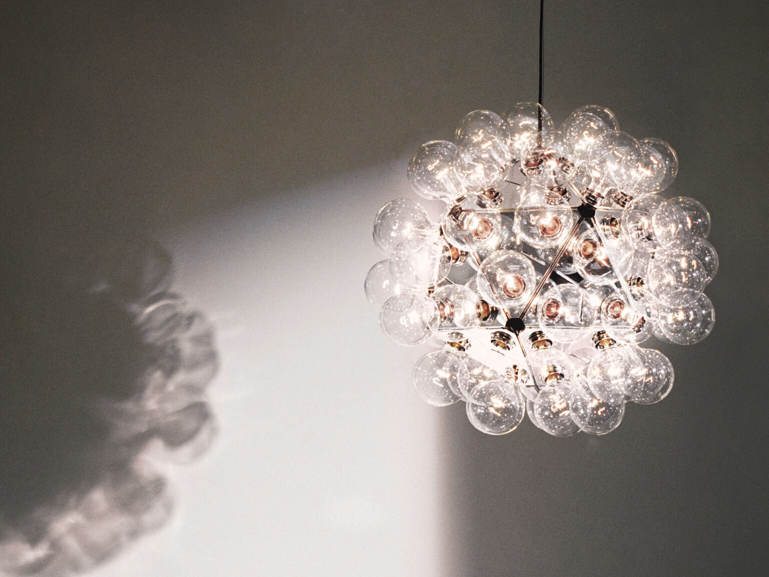 Polished aluminum geometric chandelier with dense arrangement of incandescent-style bulbs, ideal for communal spaces.