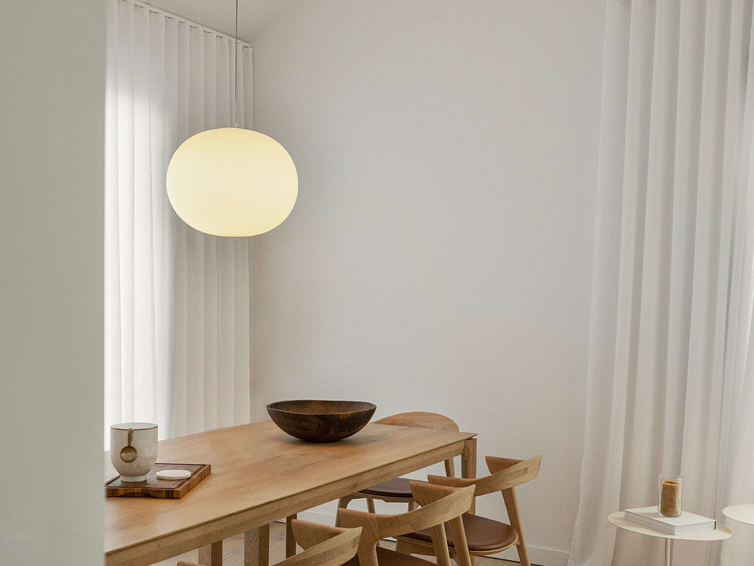 Glo‑Ball S2 above a wooden table, chrome ceiling fitting and long clear cable emphasizing verticality.