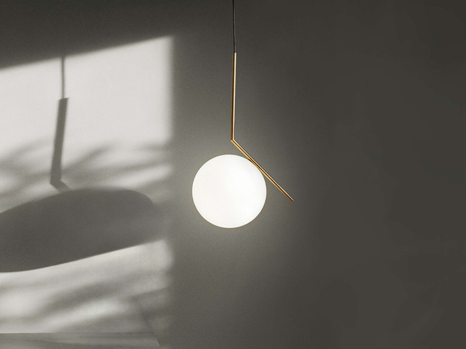 Close‑up of IC Lights S1 opal glass diffuser, showing the globe’s junction with the sleek metal tube and angled arm.