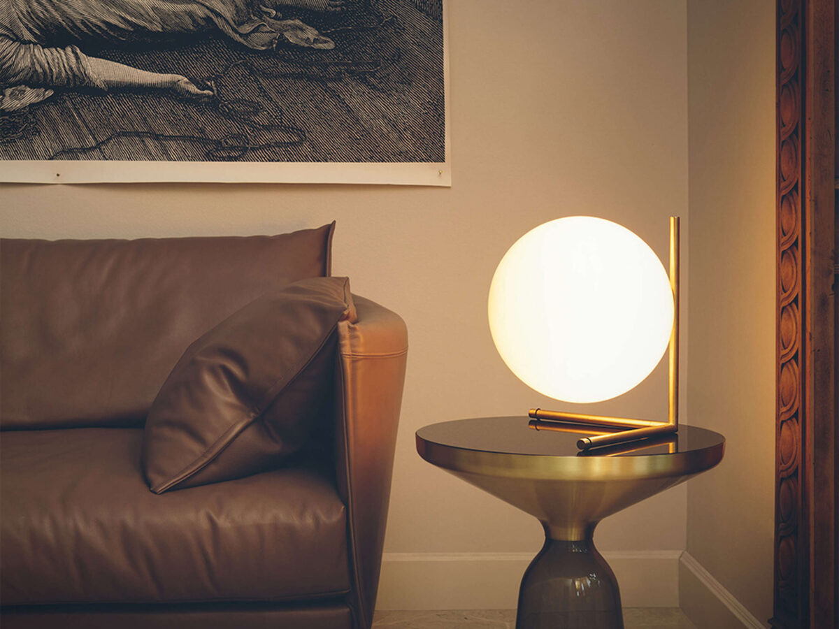 Close-up of the opaline glass globe on the IC Lights T2 by Flos, resting on a sleek brass-finished frame.
