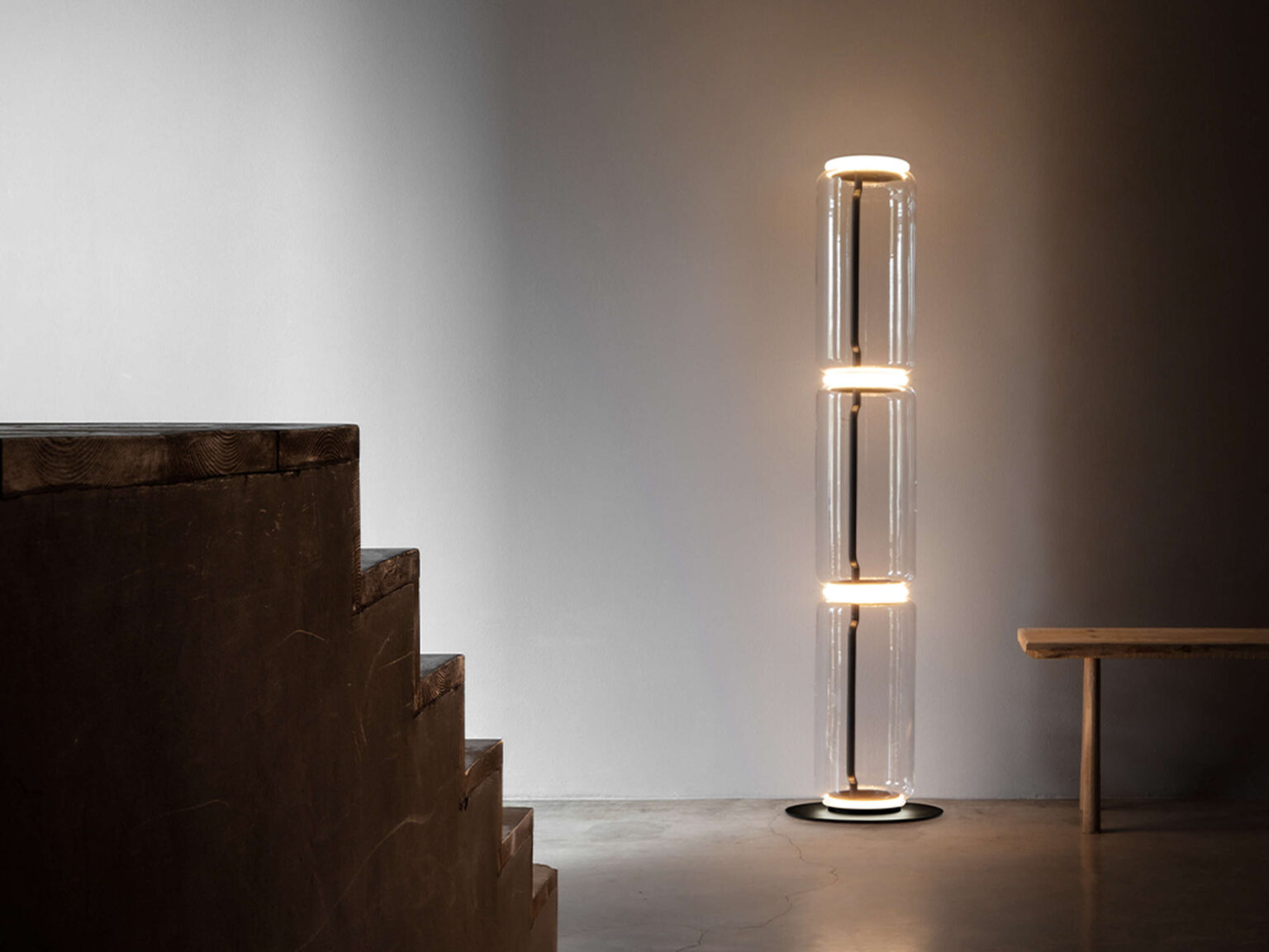 Elegant floor lamp with opal silicone diffuser rings encircling transparent glass cylinders, connected modularly.