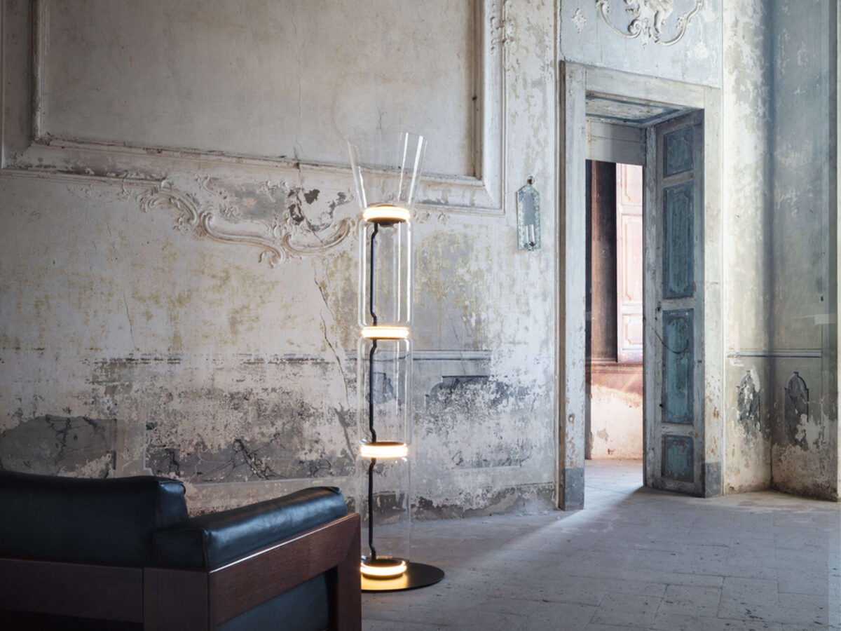 Tall sculptural floor lamp by Flos featuring crystal-clear glass cylinders and soft uplight through cone diffuser