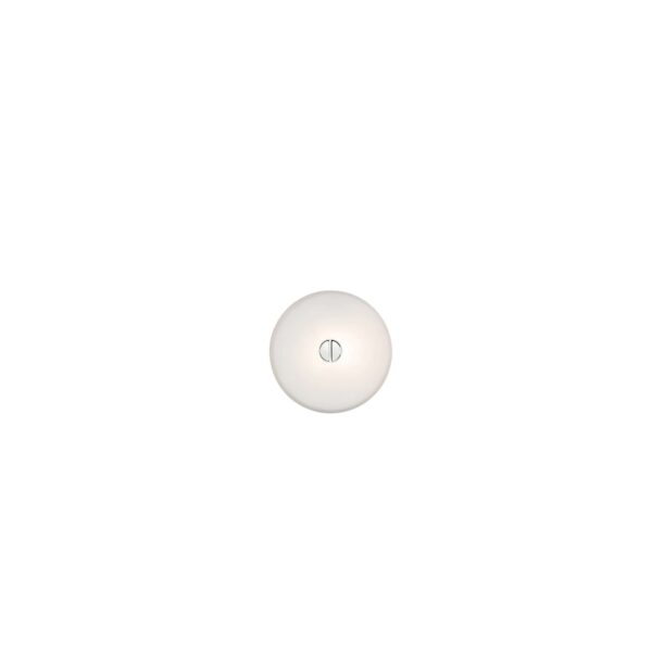 A small, round Flos Mini Button lamp, featuring a flat, white opaline glass or polycarbonate diffuser mounted flush against a wall or ceiling, providing soft, diffused light.