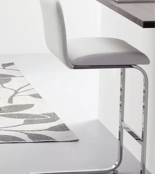 Lisa Fix bar stool by Peressini with light grey upholstered seat and back pad suspended on a cantilever chrome base, shown beside a modern kitchen island.