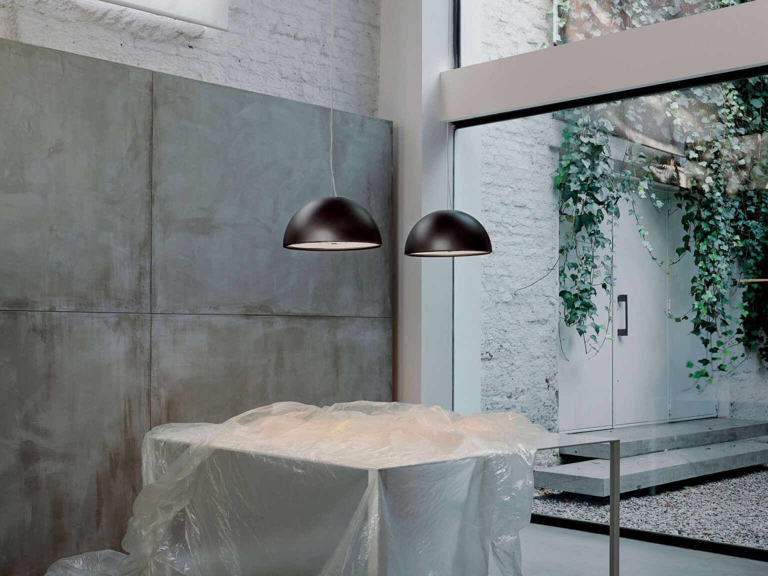 Skygarden Small lamp in bronze finish, with its domed outer shell and sculptural inner plaster relief illuminated by a warm LED glow.